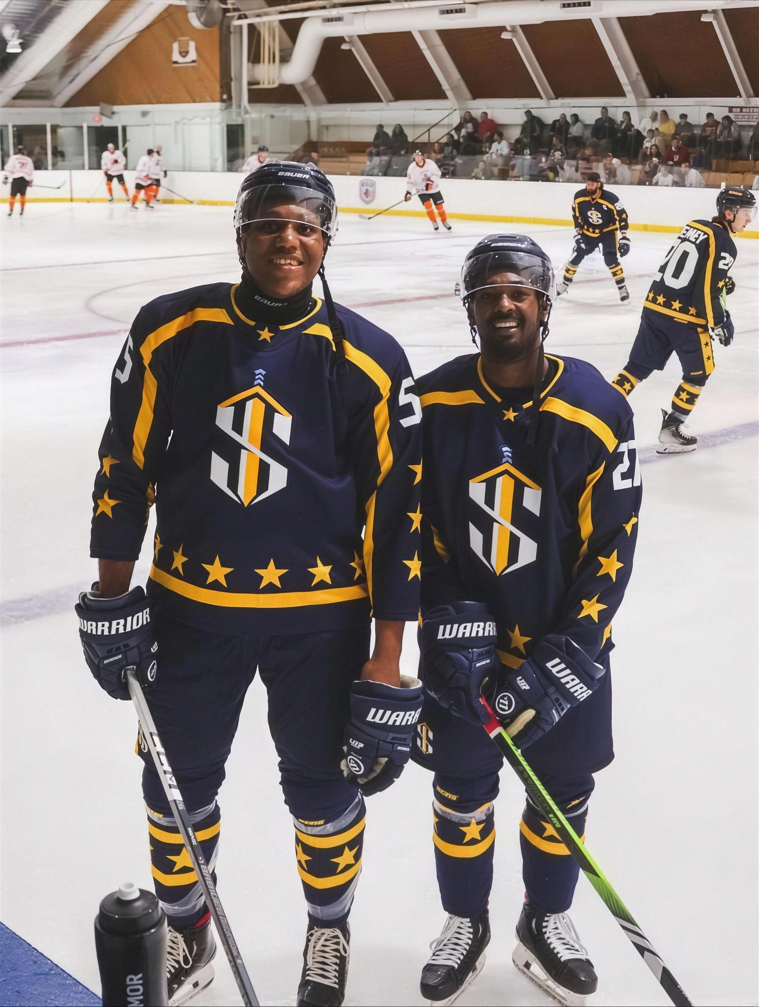 Two 43 Oak athletes in star jerseys on the ice.